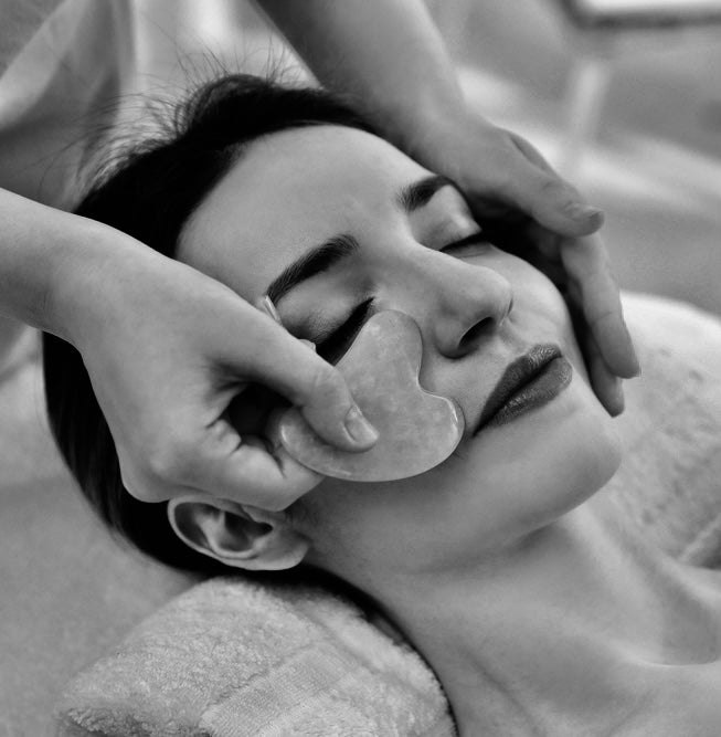 image showing the gua sha massage tool in use massaging a lady's cheek